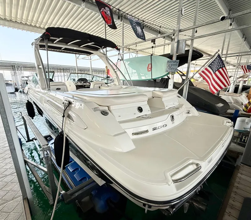 Slide: The Image of 2010 Sea Ray 250 SLX boat docked under a covered marina with American flags. - 32