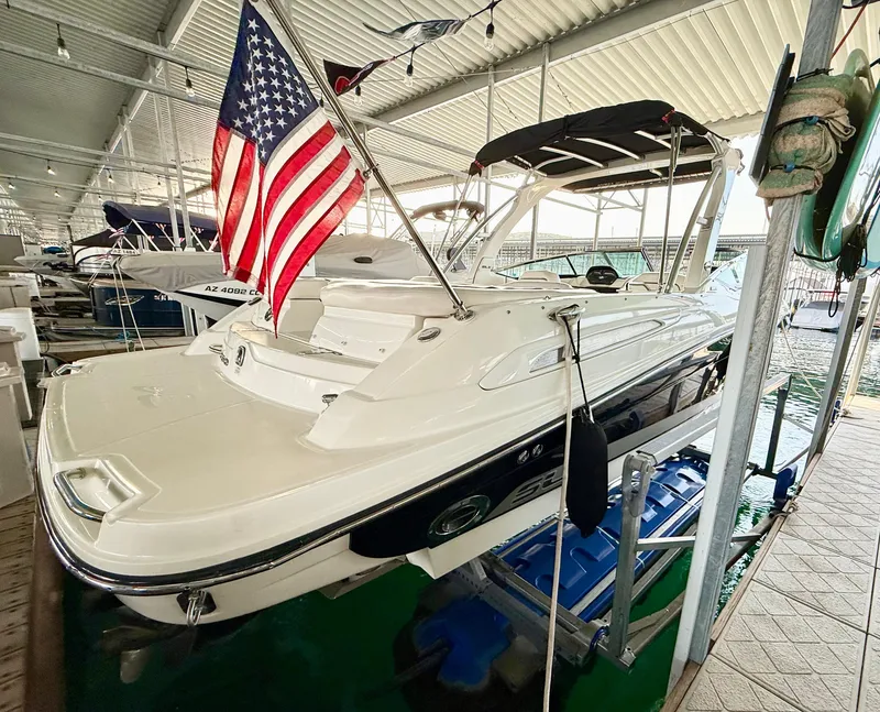 Slide: The Image of 2010 Sea Ray 250 SLX boat docked with American flag, under covered marina. - 33