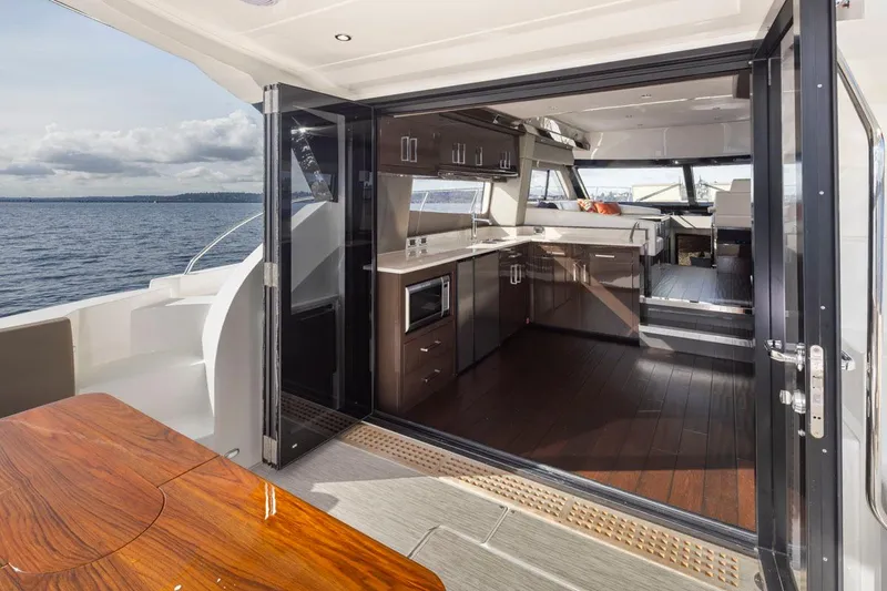 Slide: The Image of 2019 Carver C52 Command Bridge yacht interior with modern kitchen and ocean view. - 10