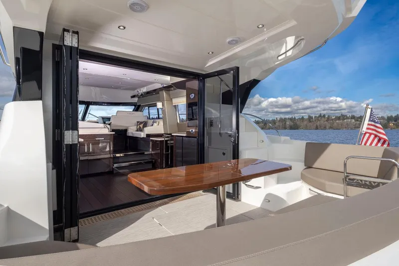 Slide: The Image of 2019 Carver C52 Command Bridge yacht interior with open deck, table, and scenic water view. - 13