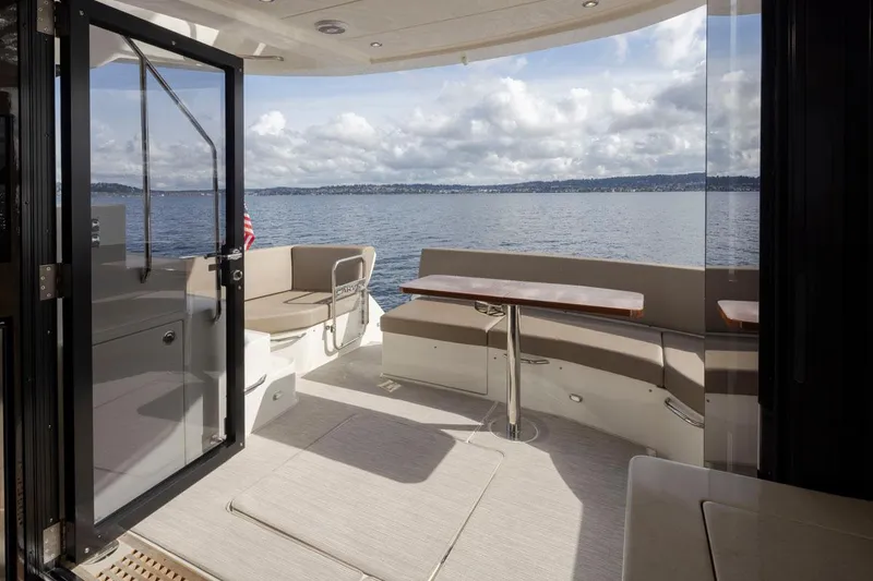 Slide: The Image of 2019 Carver C52 Command Bridge yacht interior with seating and table, overlooking serene water. - 14