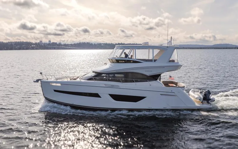 Slide: The Image of 2019 Carver C52 Command Bridge yacht cruising on a serene waterway under a cloudy sky. - 2