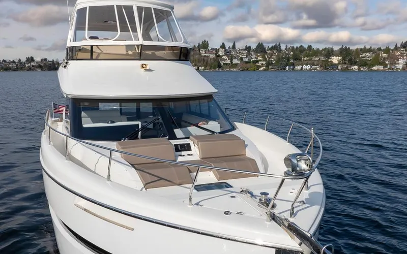 Slide: The Image of 2019 Carver C52 Command Bridge yacht on a serene lake with scenic background. - 4