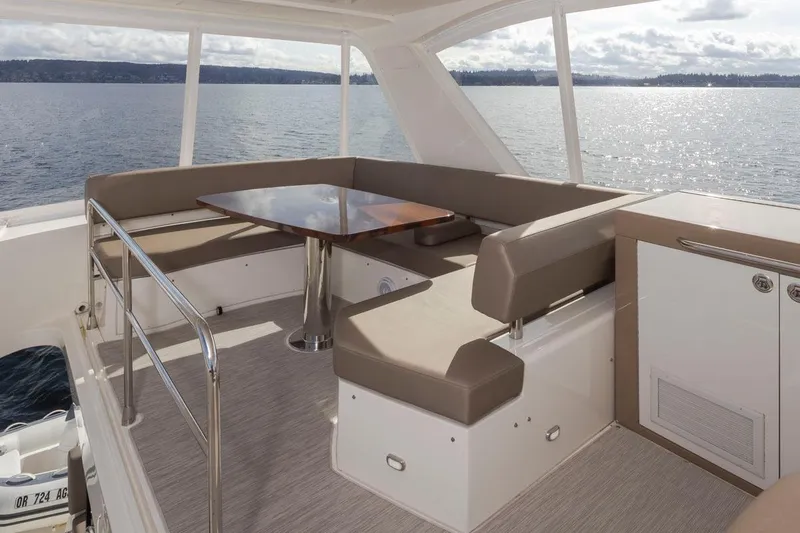 Slide: The Image of 2019 Carver C52 Command Bridge yacht interior with seating and table, overlooking serene water. - 44