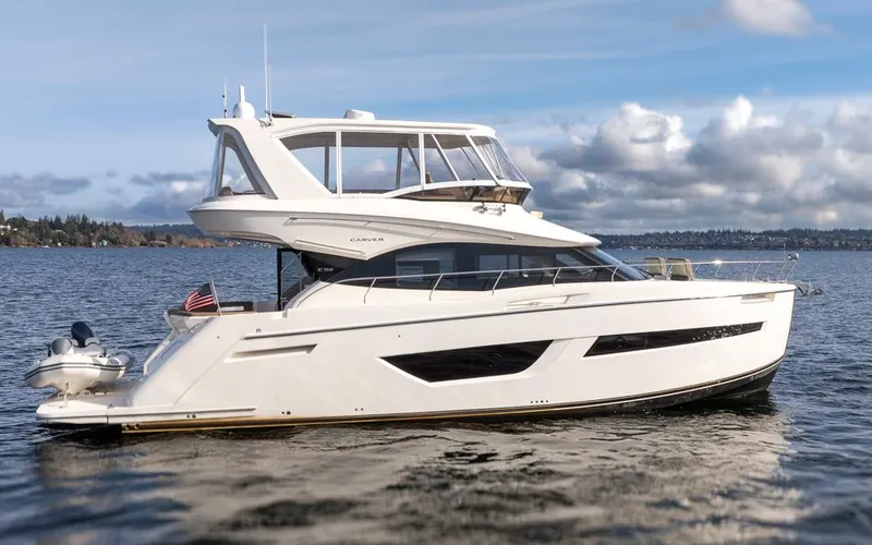 Slide: The Image of 2019 Carver C52 Command Bridge yacht on calm water under cloudy sky. - 7