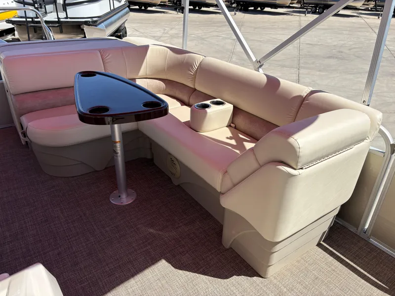 Slide: The Image of 2015 Bennington 21 SLX SPS pontoon boat interior with beige seating and a small table. - 10