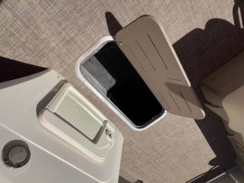 Slide: The Image of 2015 Bennington 21 SLX SPS boat storage compartment with open hatch on beige carpeted floor. - 12