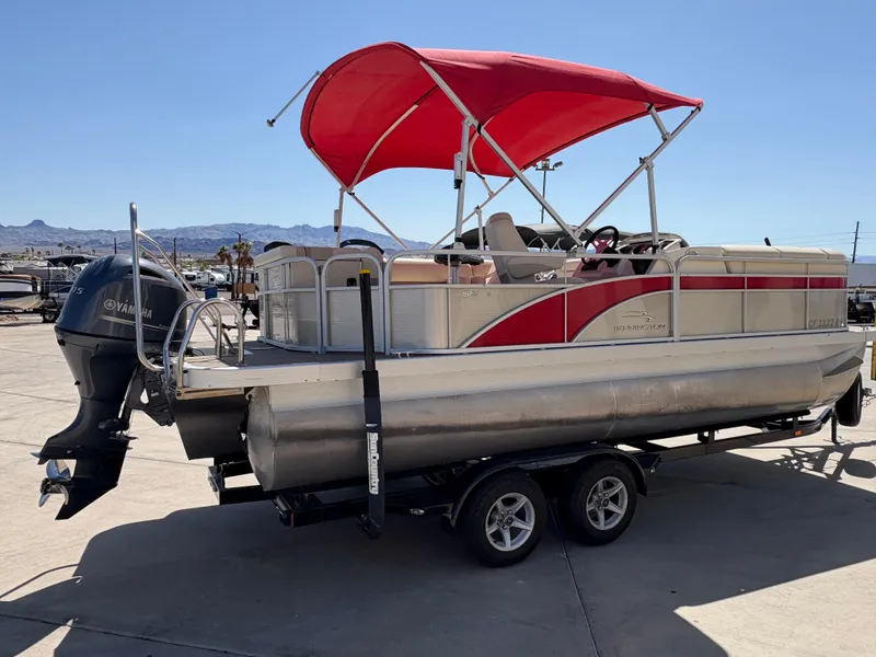 Slide: The Image of 2015 Bennington 21 SLX SPS pontoon boat with red canopy on trailer. - 2