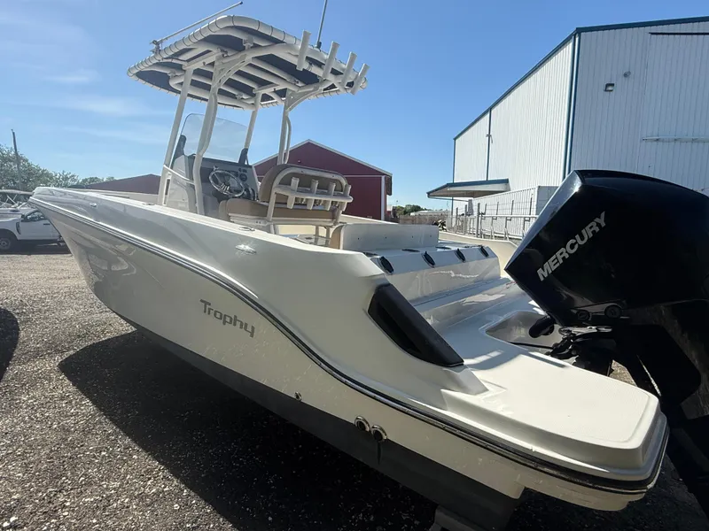 Slide: The Image of 2022 Trophy T24CC boat with Mercury engine, parked outdoors near a warehouse. - 4