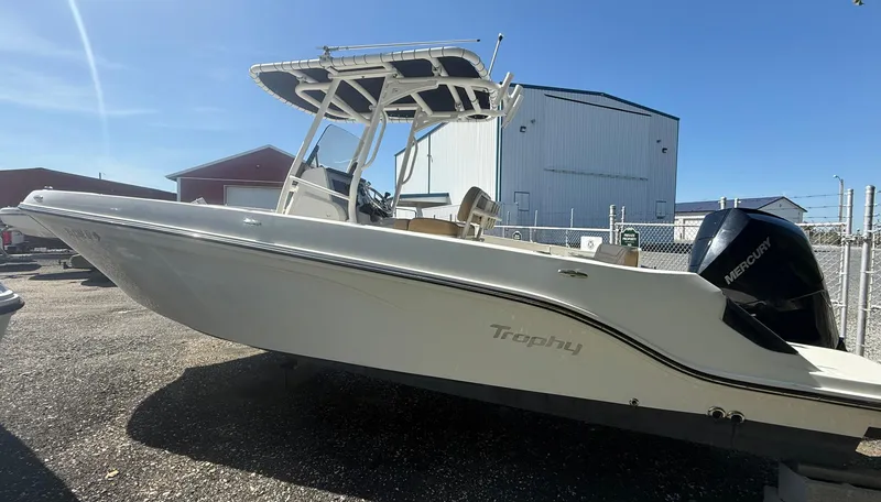 Slide: The Image of 2022 Trophy T24CC boat with Mercury engine, parked outdoors under clear blue sky. - 5