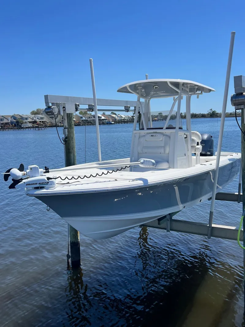 Slide: The Image of 2015 Sea Hunt BX 22 BR boat on lift over water, clear blue sky. - 0