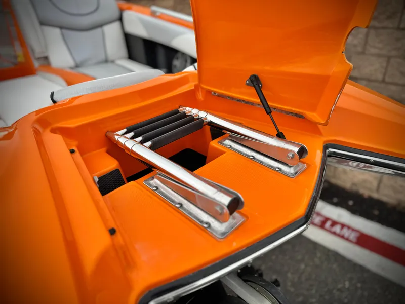 Slide: The Image of 2015 MasterCraft XStar boat with open orange storage compartment and metal components. - 12