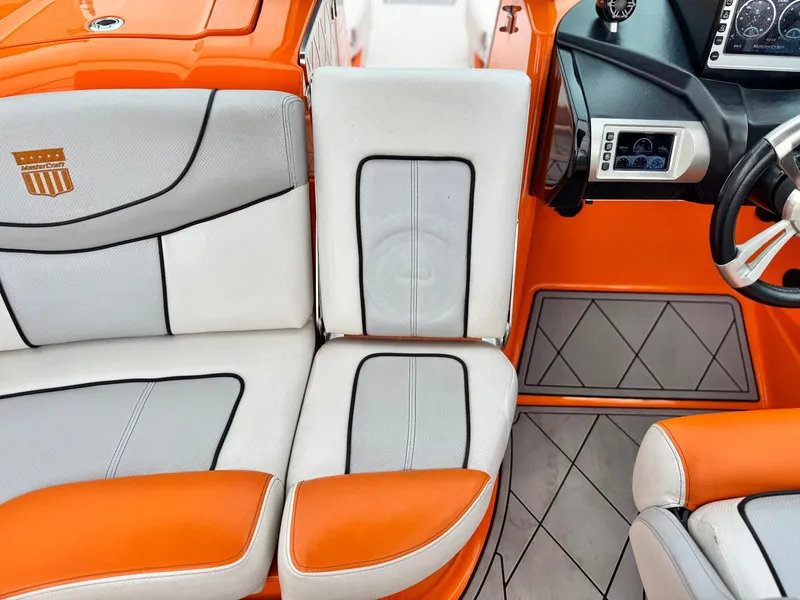 Slide: The Image of 2015 MasterCraft XStar interior with orange and white seating, modern dashboard, and sleek design. - 28