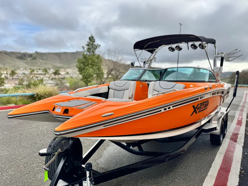 Slide: The Image of 2015 MasterCraft XStar boat in vibrant orange on a trailer, parked outdoors. - 3