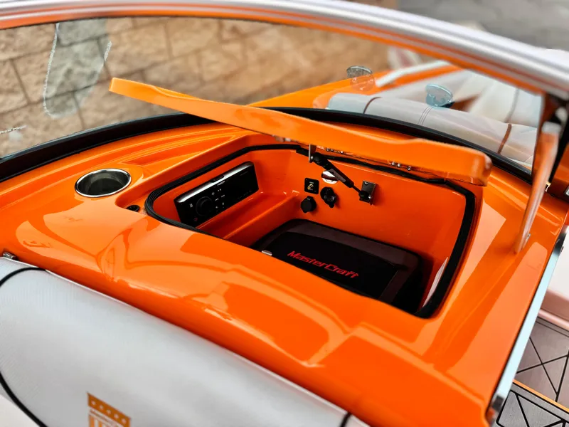 Slide: The Image of 2015 MasterCraft XStar boat interior with orange dashboard and storage compartment. - 30