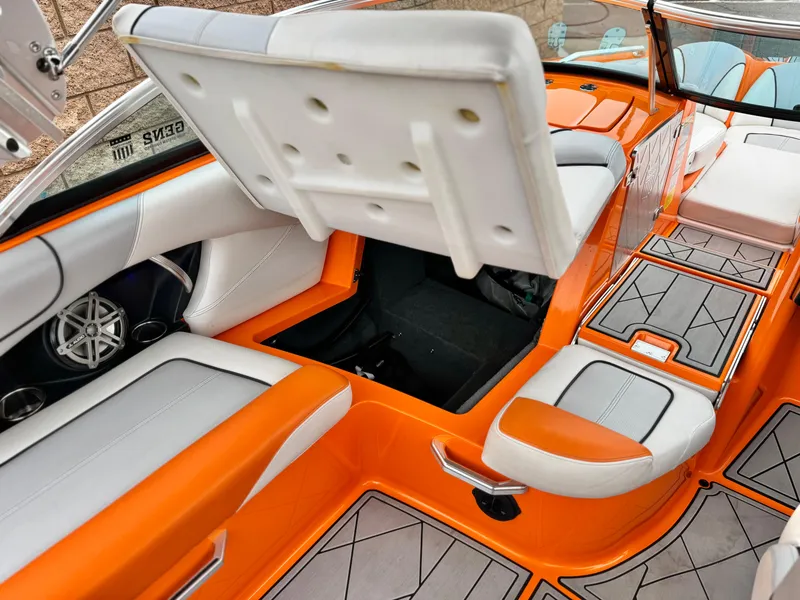 Slide: The Image of 2015 MasterCraft XStar interior with orange and white seating, showcasing storage compartment. - 32