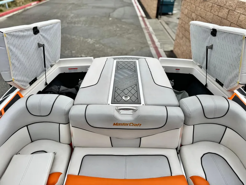 Slide: The Image of 2015 MasterCraft XStar boat interior with open storage compartments and cushioned seating. - 39