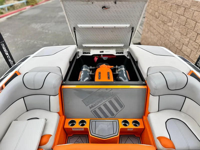 Slide: The Image of 2015 MasterCraft XStar boat interior with open engine compartment, orange and gray seating. - 40