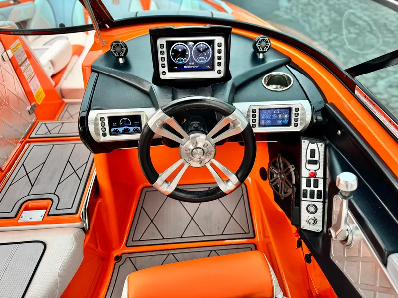 Slide: The Image of 2015 MasterCraft XStar boat dashboard with orange accents and advanced controls. - 44