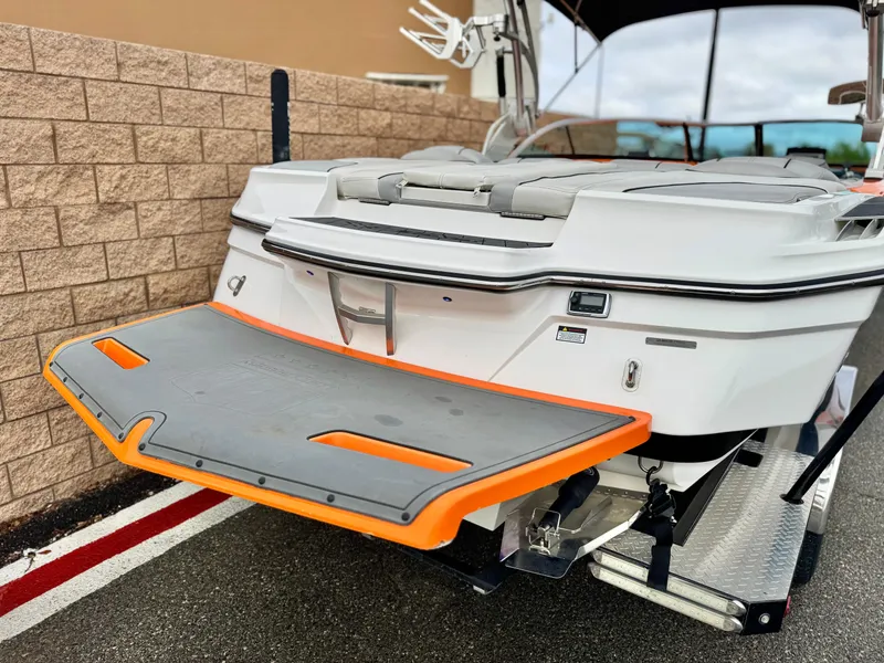Slide: The Image of 2015 MasterCraft XStar boat with orange-trimmed swim platform, parked on a trailer. - 6