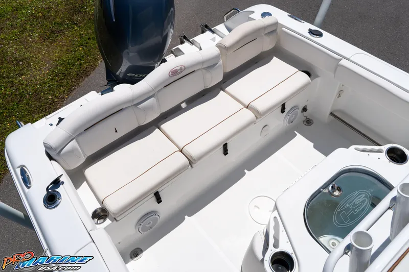 Slide: The Image of 2019 Sea Hunt Ultra 234 boat interior with white cushioned seating and motor. - 18