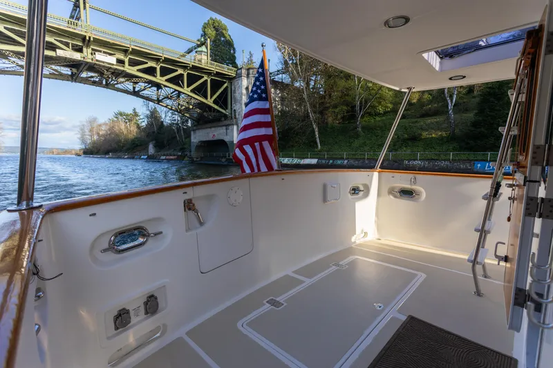 Slide: The Image of Selene 47 yacht deck, 2003 model, under a bridge with American flag, scenic waterway view. - 12