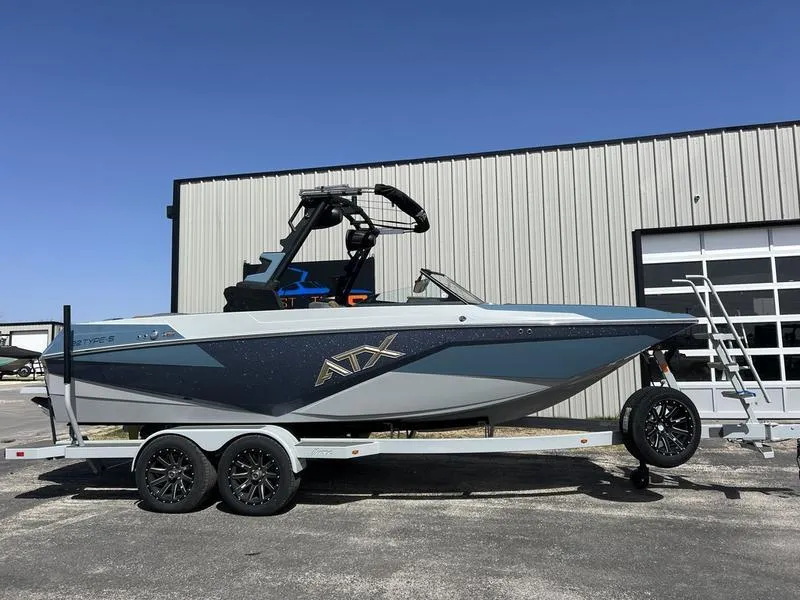 Slide: The Image of 2025 ATX Surf Boats 22 Type-S on trailer, parked outside industrial building. - 0