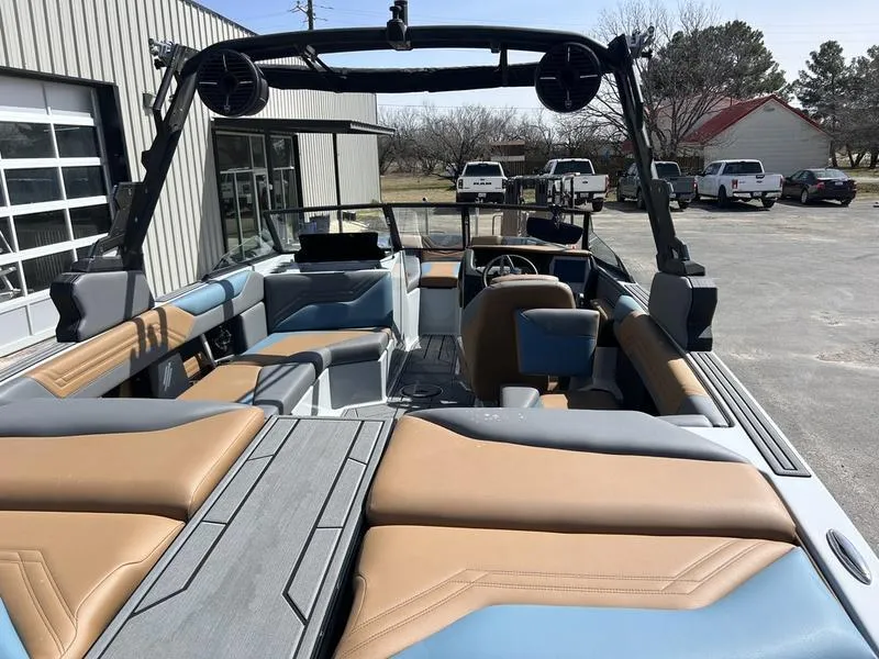 Slide: The Image of 2025 ATX Surf Boats 22 Type-S interior with tan and blue seating, parked outdoors. - 6