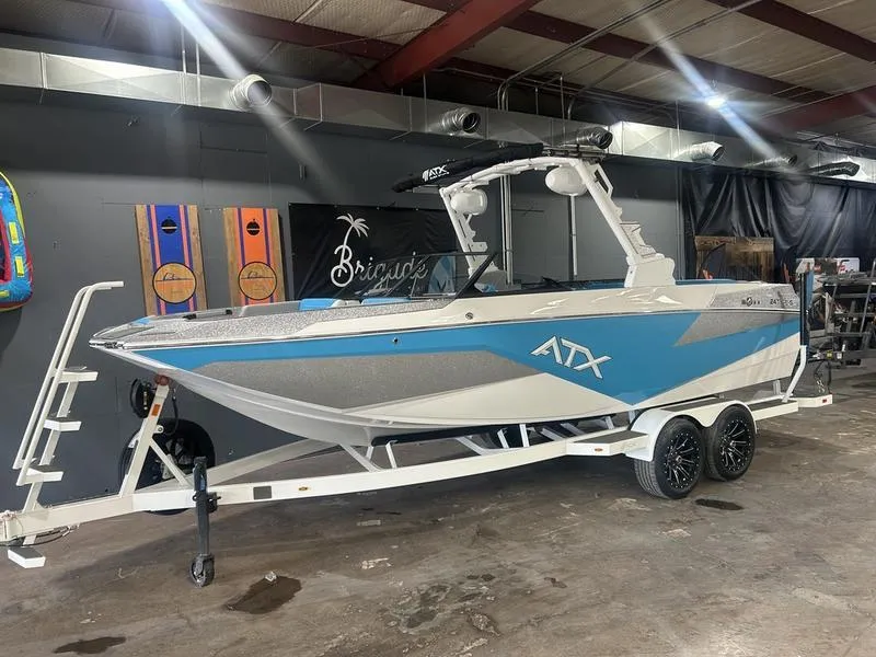 Slide: The Image of 2025 ATX Surf Boats 24 Type-S in showroom, blue and white design on trailer. - 0