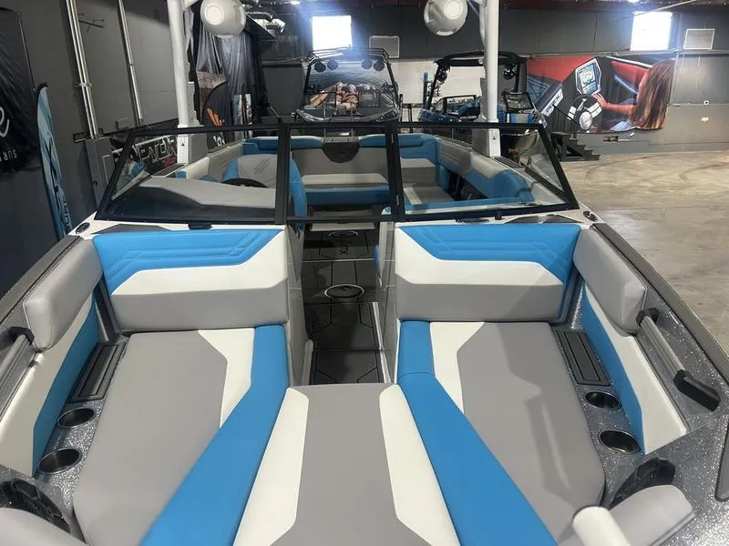 Slide: The Image of 2025 ATX Surf Boats 24 Type-S interior with blue and gray seating in a showroom. - 2