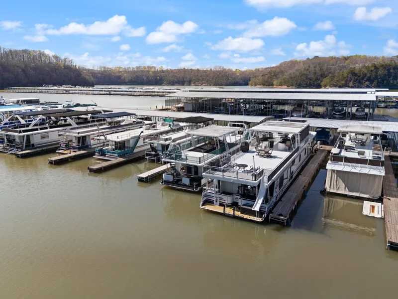 Slide: The Image of 1998 Sharpe 16 X 80 Widebody Houseboat docked at a marina with scenic background. - 11