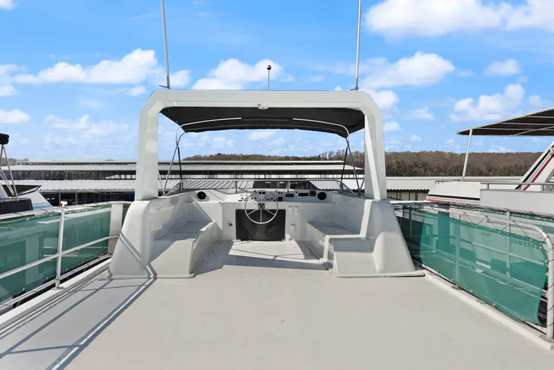 Slide: The Image of 1998 Sharpe 16 X 80 Widebody Houseboat with spacious deck and helm, docked under blue sky. - 17