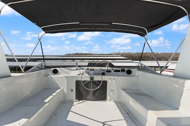 Slide: The Image of 1998 Sharpe 16 X 80 Widebody Houseboat helm with canopy, docked under blue sky. - 18