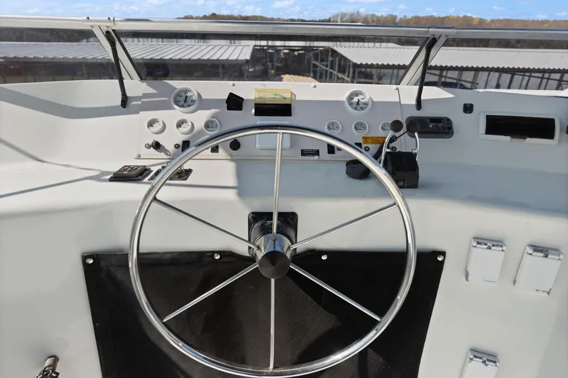 Slide: The Image of 1998 Sharpe houseboat helm with steering wheel and control panel, docked under clear skies. - 19