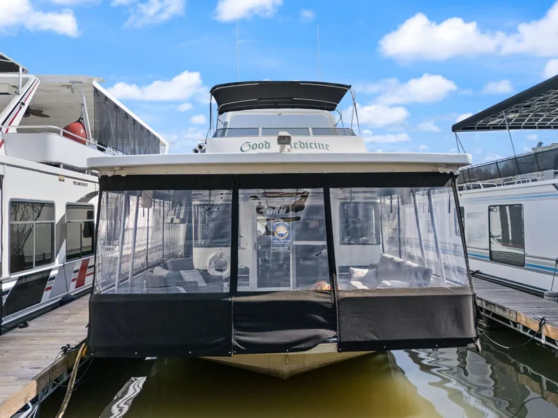 Slide: The Image of 1998 Sharpe 16 X 80 Widebody Houseboat docked, featuring enclosed deck and clear skies. - 2