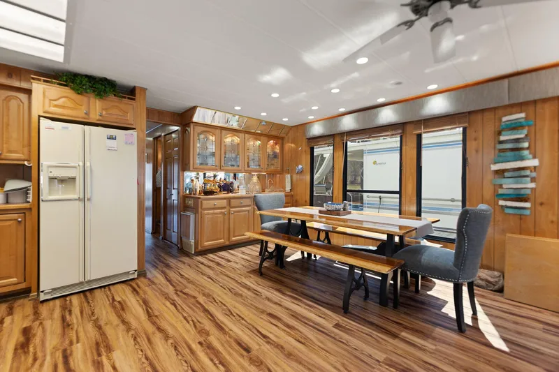 Slide: The Image of 1998 Sharpe houseboat interior with wooden flooring, dining area, and kitchen cabinetry. - 29