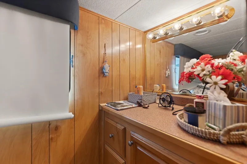 Slide: The Image of 1998 Sharpe houseboat interior with wood paneling, vanity, and decorative flowers. - 40