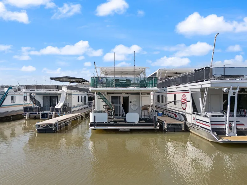 Slide: The Image of 1998 Sharpe 16 X 80 Widebody houseboat docked on calm water under a clear blue sky. - 8