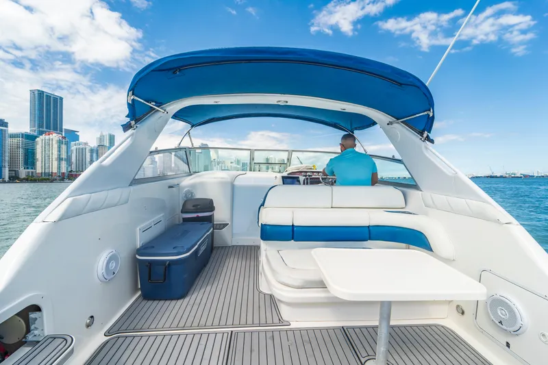 Slide: The Image of 1997 Sea Ray 330 Sundancer yacht with blue canopy, city skyline in background. - 1