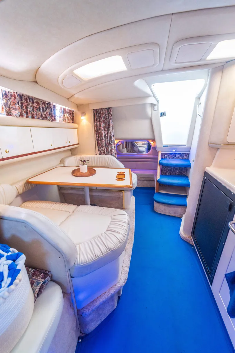 Slide: The Image of Interior of 1997 Sea Ray 330 Sundancer yacht with blue flooring and cozy seating area. - 10