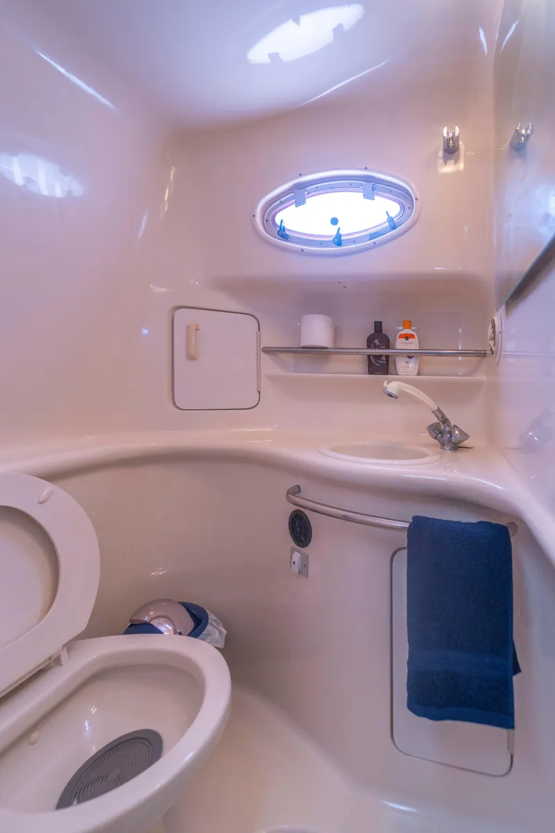 Slide: The Image of 1997 Sea Ray 330 Sundancer bathroom with porthole, toilet, and sink. - 12