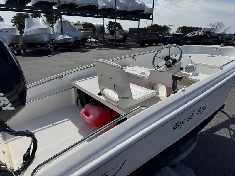 Slide: The Image of 2012 Boston Whaler 130 Super Sport boat with white interior and steering wheel, docked outdoors. - 6