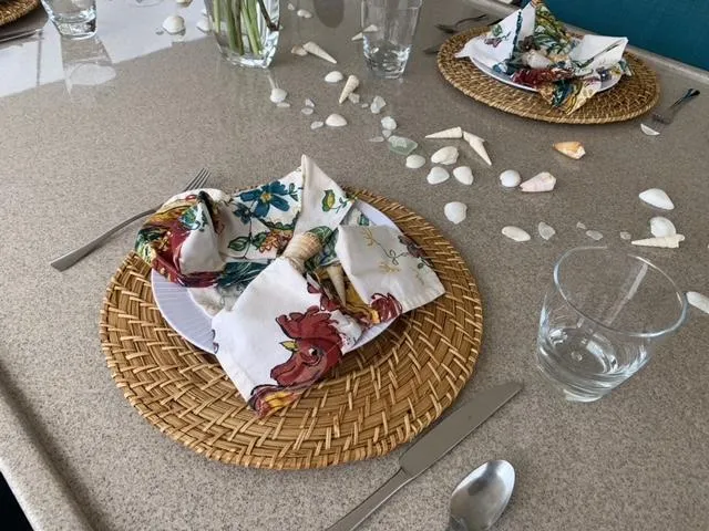 Slide: The Image of Elegant table setting with floral napkins, seashells, and woven placemats on a beige surface. - 18