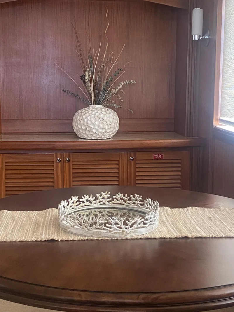 Slide: The Image of Elegant wooden interior with decorative vase and coral centerpiece on Allseas Expedition yacht, 2018. - 24