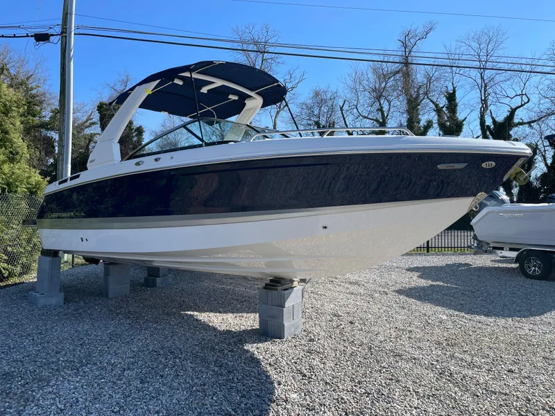 Slide: The Image of 2025 Chaparral 267 SSX boat displayed on gravel lot with blue canopy. - 1