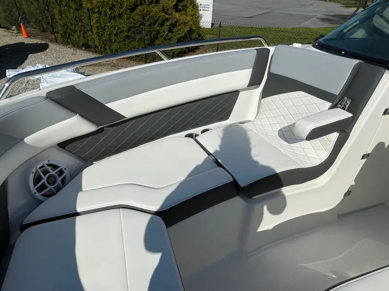 Slide: The Image of 2025 Chaparral 267 SSX boat interior with white and gray seating, diamond stitching, and speaker. - 15