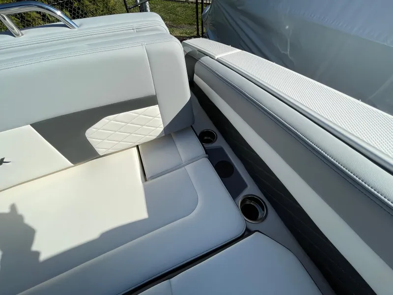 Slide: The Image of 2025 Chaparral 267 SSX boat interior with white leather seating and cup holders. - 49