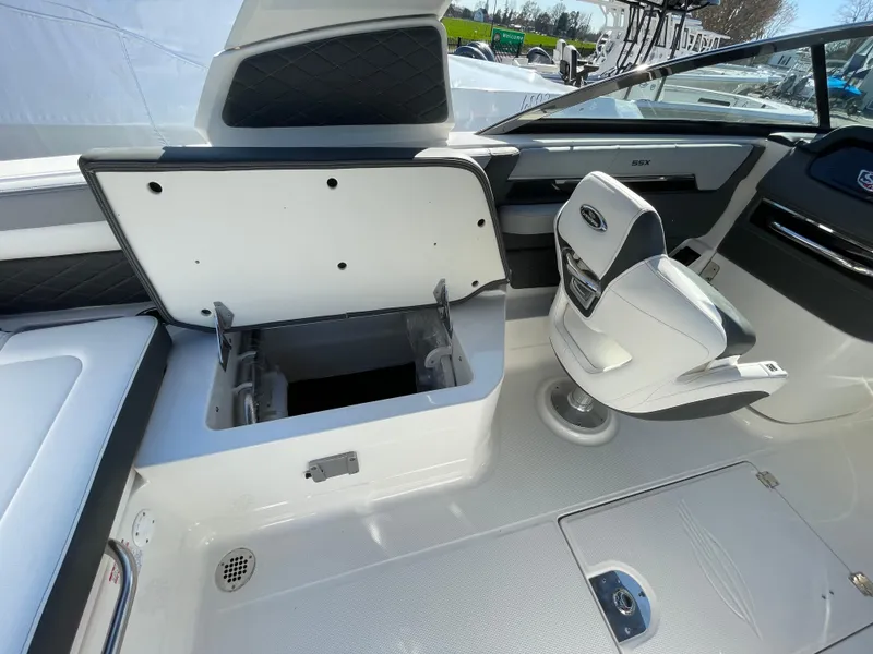 Slide: The Image of 2025 Chaparral 267 SSX boat interior with open storage compartment and swivel seat. - 48