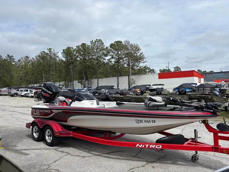Slide: The Image of 2011 Nitro Z-8 boat on red trailer in parking lot, surrounded by trees and vehicles. - 4