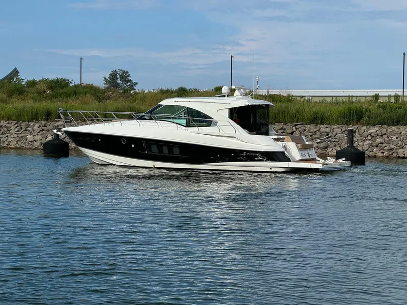 The Image of 2014 Cruisers Cantius yacht on calm water near a rocky shoreline. - 0